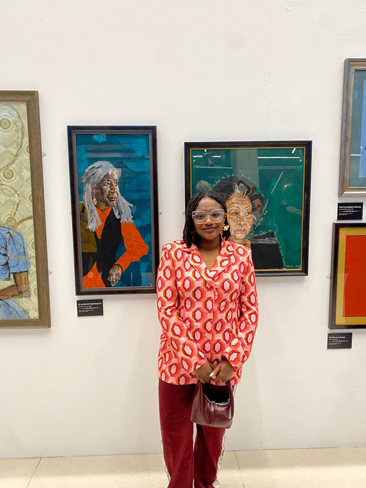 artist Yvadney Davis infront of her portraits of Black British Women at Leicester Gallery for 100 Black Women Who Have Made a Mark Exhibition